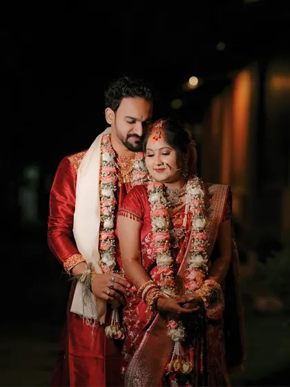 A tender night-time portrait of the couple after their wedding ceremony, still in their beautiful red and white wedding attire.