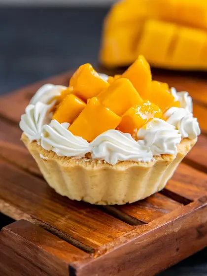 Our Mango Custard Tart is a bite of sunshine. A buttery, crisp tart shell is filled with creamy custard and topped with a generous amount of fresh, juicy mango.