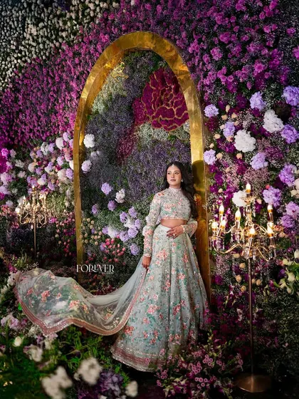 The bride poses against the backdrop of the heavenly floral arch, her flowing lehenga complementing the dreamy, nature-inspired design.