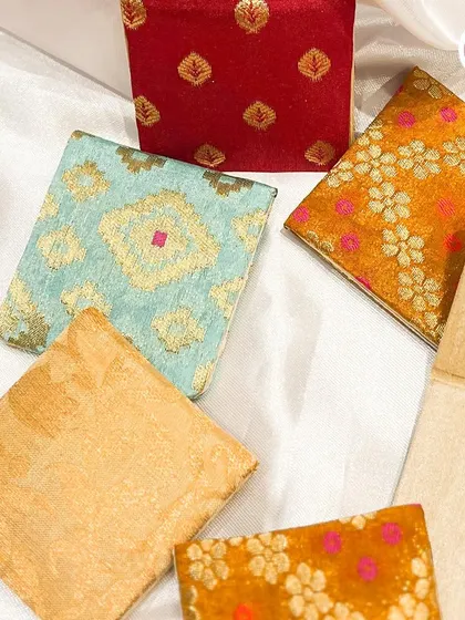 A variety of our custom fabric coin holders, available in different colors and patterns like brocade and bandhani.