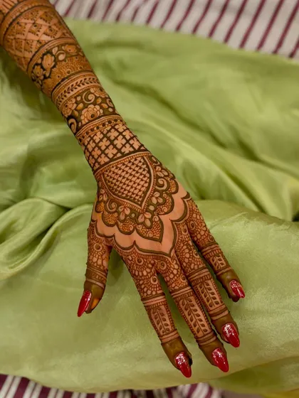A single-hand view of a wedding mehendi, showing the intricate heart-shaped design on the back of the hand.