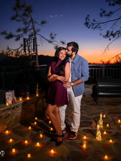An intimate moment with a forehead kiss against the beautiful colors of a sunset sky, surrounded by the romantic glow of candles.