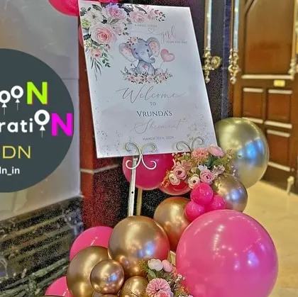 A vibrant welcome sign for a baby girl's shower, decorated with pink and gold balloons to match the main decor.
