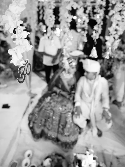 An artistic, blurry black and white shot of the couple at the mandap, with the 'Om' symbol in focus. This creative composition adds a spiritual and moody feel.