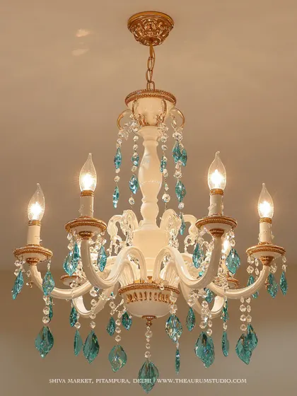 A classic white and gold chandelier adorned with striking turquoise crystals. I love adding a pop of color like this to a traditional design; it personalizes the piece and turns it into a unique family heirloom.