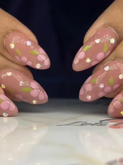 A close-up of the delicate floral and rhinestone nail art.