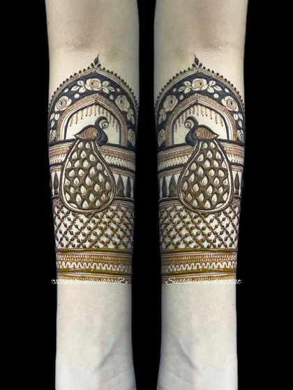 A striking peacock arm band design, shown in a mirrored image to highlight its symmetry.