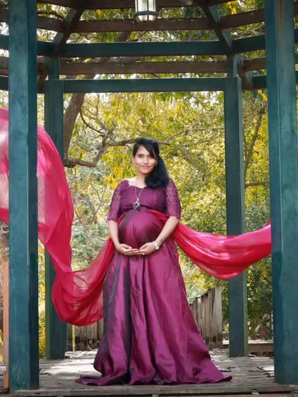 A beautiful maternity portrait in a gazebo, featuring a wine-colored flying gown. The long trail adds a touch of royalty and elegance to the photo.