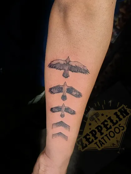 A conceptual tattoo showing the evolution of a bird in flight, transforming into arrows pointing forward. It symbolizes growth, progress, and always moving ahead.