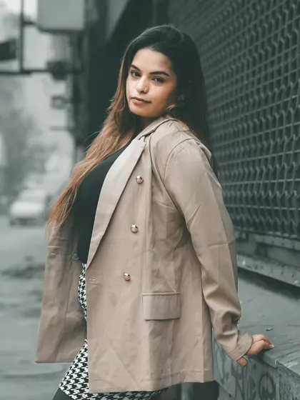 Using the texture of the metal gate as a backdrop, this portrait has a distinctly urban feel. The model's pose is relaxed but confident, perfect for a street style feature.