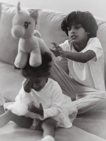The funny, unpredictable interactions between siblings are what make family photoshoots so special. Here, an older brother playfully balances a toy on his little sister's head, a perfect example of an authentic, unscripted memory.