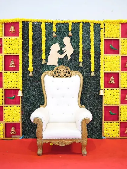 A classic Seemantham backdrop with yellow marigold panels and a central mother and child silhouette. The design is simple yet traditional, perfect for an intimate baby shower ceremony.