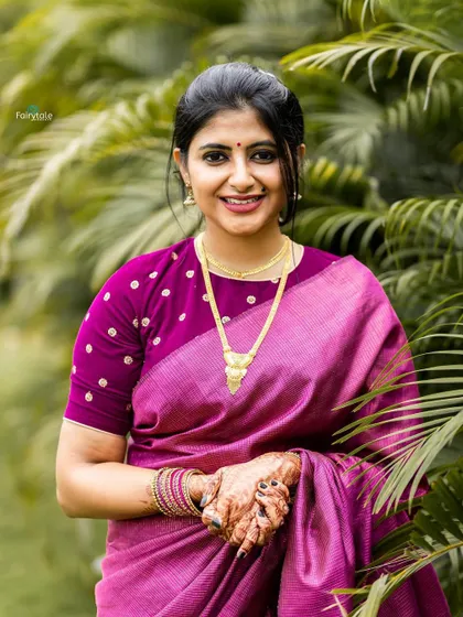 A smiling portrait in a pink saree, capturing a moment of joy.