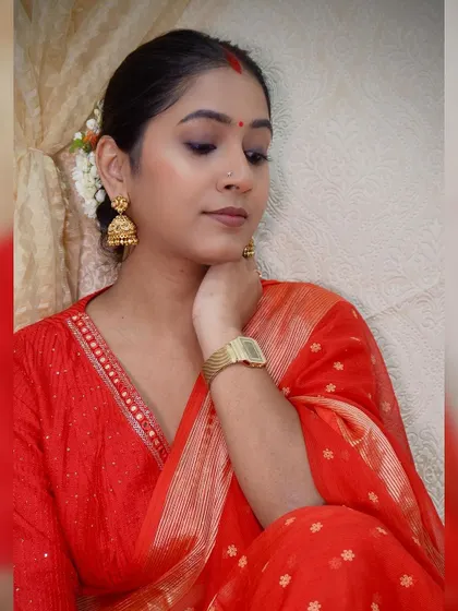 A candid moment from my Nayanthara-inspired look. The simplicity of the red saree is enhanced with traditional gold jhumkas and fresh jasmine flowers in my hair, creating a classic South Indian festive style.