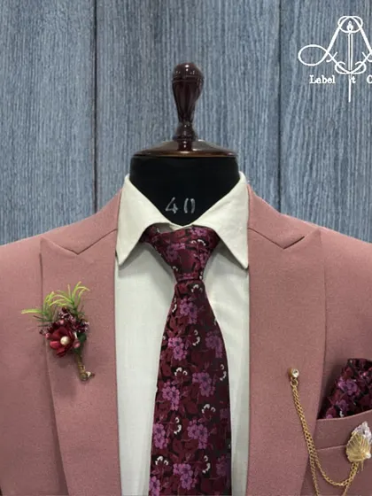 A closer look at the dusty rose suit jacket. The details matter, from the floral lapel pin to the patterned tie and pocket square, all coming together to create a harmonious and unique outfit.