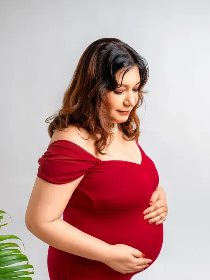 A simple, elegant portrait. Even without the full set, a single palm leaf adds a touch of nature and texture to this classic maternity pose in a red dress.