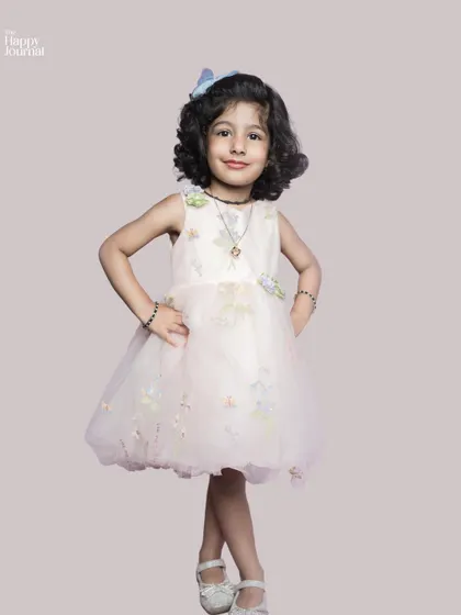 A little girl in a pretty pink dress, posing with confidence and a sweet smile. A classic and beautiful child portrait.
