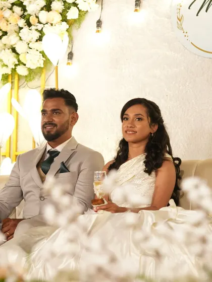 A happy couple at their wedding reception. The bride is wearing her custom one-shoulder white gown, a perfect blend of modern design and classic elegance.