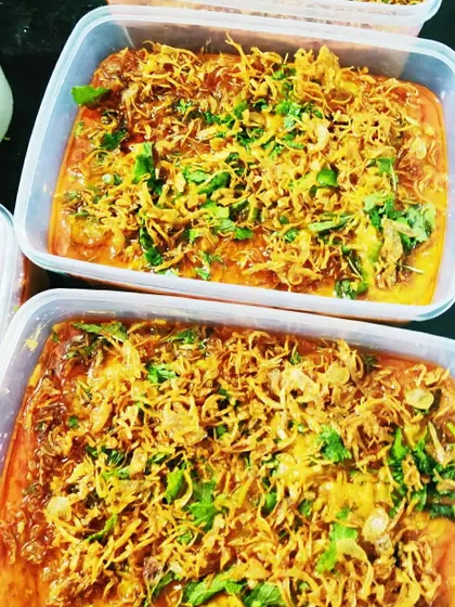 Takeaway boxes of our Mutton Khichda, garnished with a generous amount of birista (fried onions). This dish is a hearty and nutritious option.