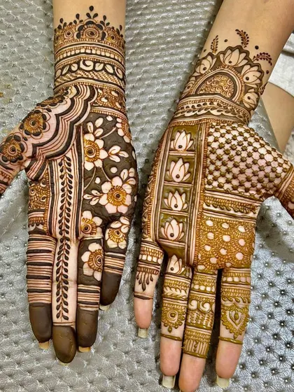 A designer mehendi with exquisite floral patterns. One hand features a dense floral jaal, while the other has modern, spaced-out lotus motifs.