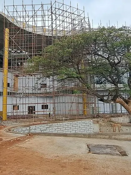 A close-up of the construction at Inorbit Vizag, where the building's curved form wraps around a preserved tree. This highlights our commitment to biophilic design even in large-scale commercial projects.