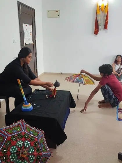 A participant interacts with a puppet during our workshop. We use colorful props like these traditional umbrellas to make the storytelling even more engaging and visually rich.
