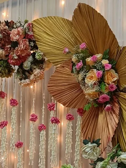 A close-up of the pastel floral decor. The combination of dried palm leaves, roses in shades of pink and peach, and hanging jasmine strings creates a beautiful, textured backdrop.