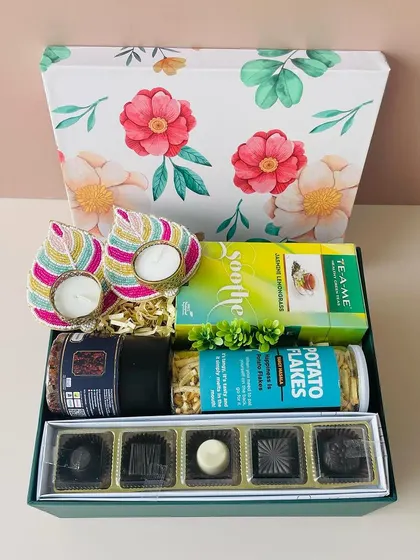 This floral lid box is curated with gourmet chocolates, healthy snacks, and beaded leaf-shaped t-light holders.
