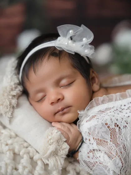 An even tighter close-up on the baby's face, highlighting the delicate headband and her perfectly peaceful expression.