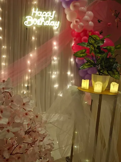 A side view of the 12th birthday decor, highlighting the 'Happy Birthday' neon sign and the fairy light curtain.