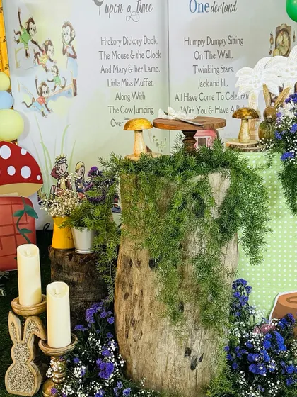 A close-up of the ONEderland setup, showing a tree stump dessert stand covered in moss, surrounded by candles and storybook elements, bringing the enchanted forest theme to life.