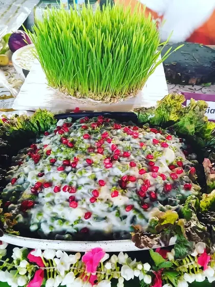 A creamy Russian salad topped with pomegranate seeds, beautifully presented with a floral garland.