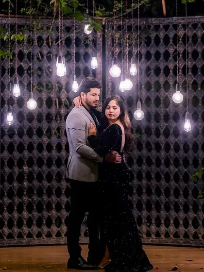 This couple's chemistry is perfectly captured in this shot, with dramatic lighting from hanging bulbs. Her black sequin gown adds to the moody, romantic atmosphere.