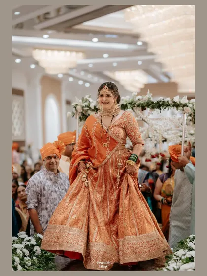 The bride's joyful entrance, her orange lehenga swirling around her. This candid portrait captures her happiness and the energy of the moment.