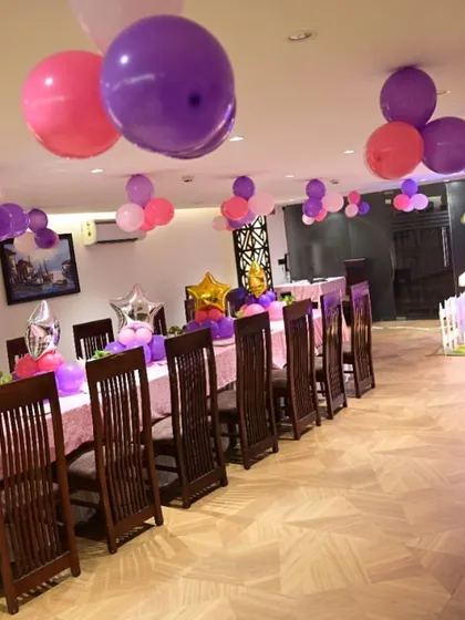 The guest dining area at a princess-themed birthday party. The long table is decorated with balloon centerpieces and the ceiling has floating balloon clusters.
