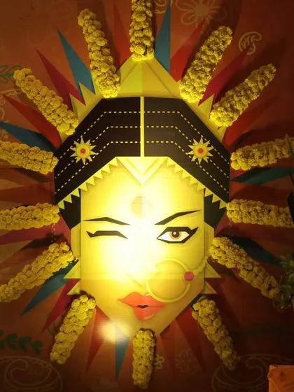 A quirky and artistic lighted installation of a winking bride's face, decorated with marigolds, adding a fun and modern touch to the Haldi decor.