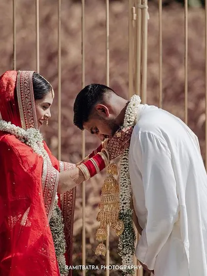 The groom bows respectfully as the bride places the garland on him during their Varmala ceremony.