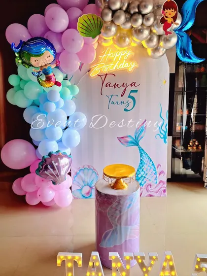 A simple and sweet mermaid theme, ideal for smaller spaces. The decor features a mermaid-tail balloon, a custom backdrop, and a neon "Happy Birthday" sign.