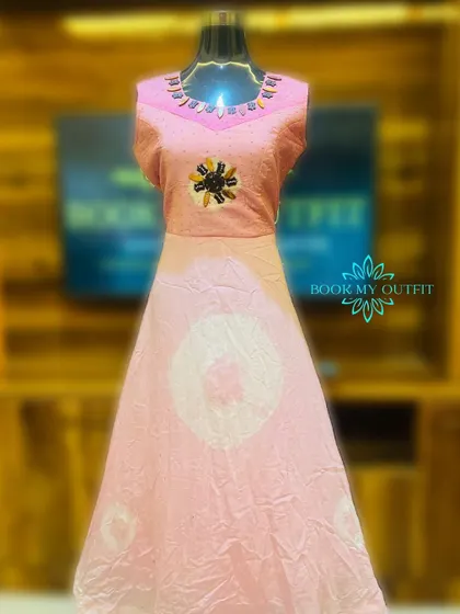 A unique long gown with a pink tie-dye effect on the skirt. The bodice features a simple beaded neckline and a central embroidered motif, making it a subtly artistic choice.
