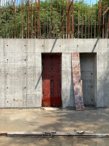 A completed in-situ concrete wall with openings for doorways. The regular pattern of tie-rod holes is a deliberate part of the architectural aesthetic.