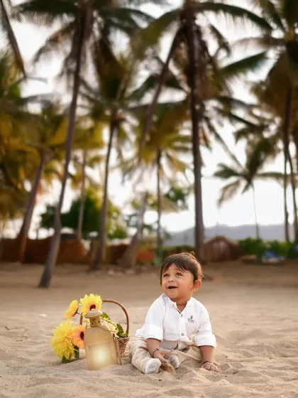 A solo portrait of a toddler on the beach at sunset. The warm light and palm tree background create a beautiful, serene atmosphere for this outdoor shoot.