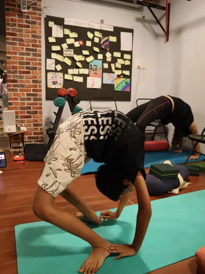 This student works on his Urdhva Dhanurasana (Upward Bow Pose), showing great strength in his arms and legs to lift his body.