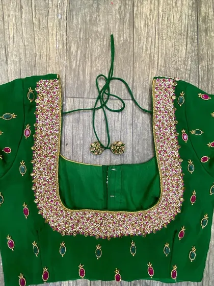 This green blouse has a heavily beaded neckline. The rest of the blouse has scattered motifs made with green and red stones.