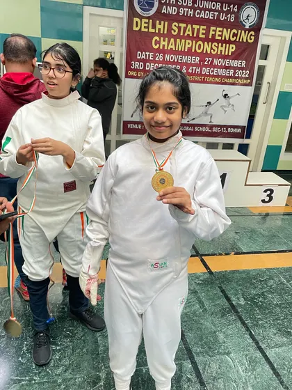 A young gold medalist in her fencing whites, right after her victory at the state championship.