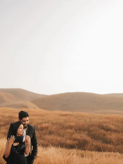 A beautiful portrait with the couple framed against a vast expanse of golden fields and rolling hills, creating a sense of peace and togetherness.