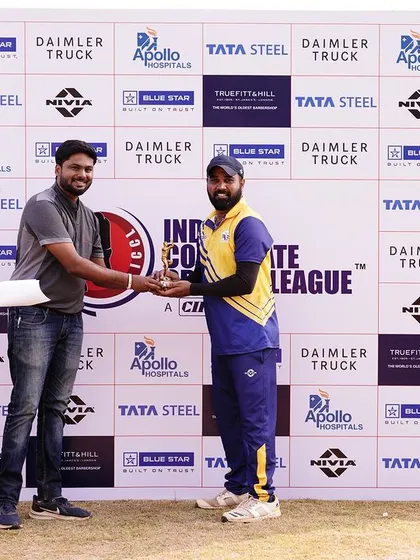 An awards ceremony in progress at the cricket league, with a player receiving an award in front of the branded sponsor backdrop.