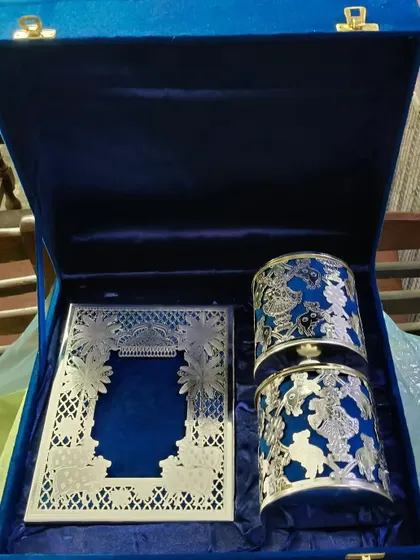 This is an example of a truly luxurious wedding invitation set. It features an intricate silver laser-cut card and matching favors, all presented in a royal blue velvet box, designed to be a treasured keepsake.