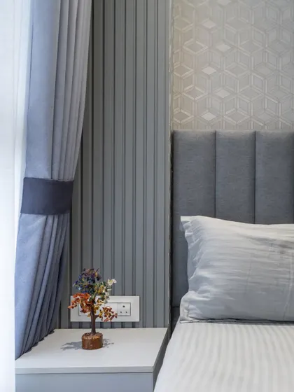 This bedroom uses a cool gray color palette with vertical fluting on the walls and matching curtains, creating a serene and cohesive look.