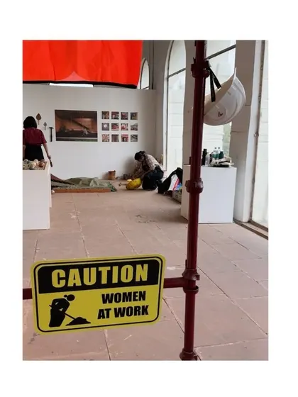 Another view of our "Women at Work" sign at the IAADB exhibition, with our team setting up in the background, reinforcing our core mission.