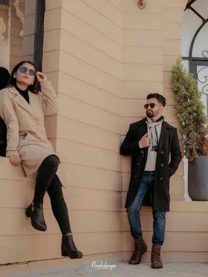 A cool, editorial-style portrait of a couple posing against a modern building, showcasing a more contemporary and fashionable pre-wedding style.